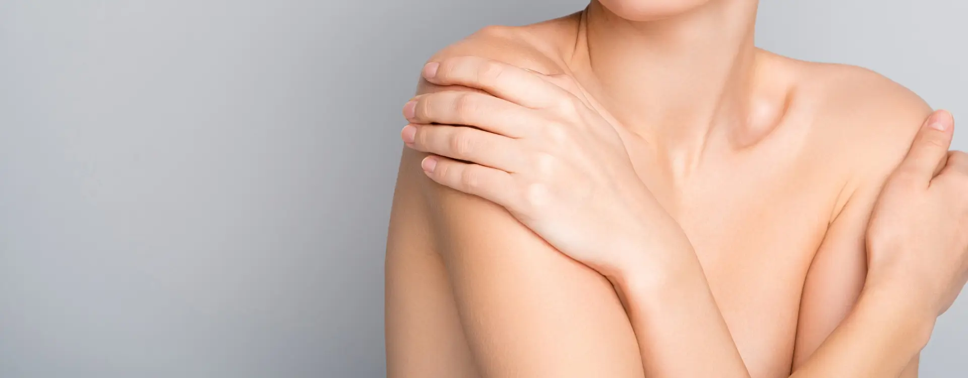 A woman with bare shoulders and her arms crossed over her chest, the photo on Bellava's breast reduction page