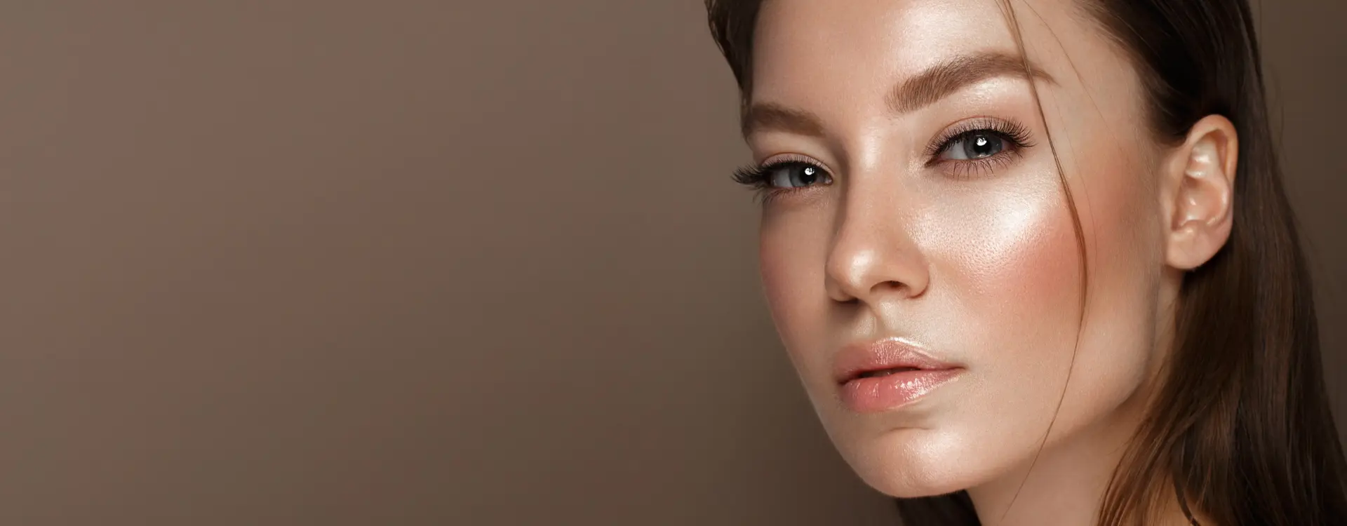 A woman with glowing skin and swept-back hair against a warm brown backdrop, the photo on Bellava’s injectables page