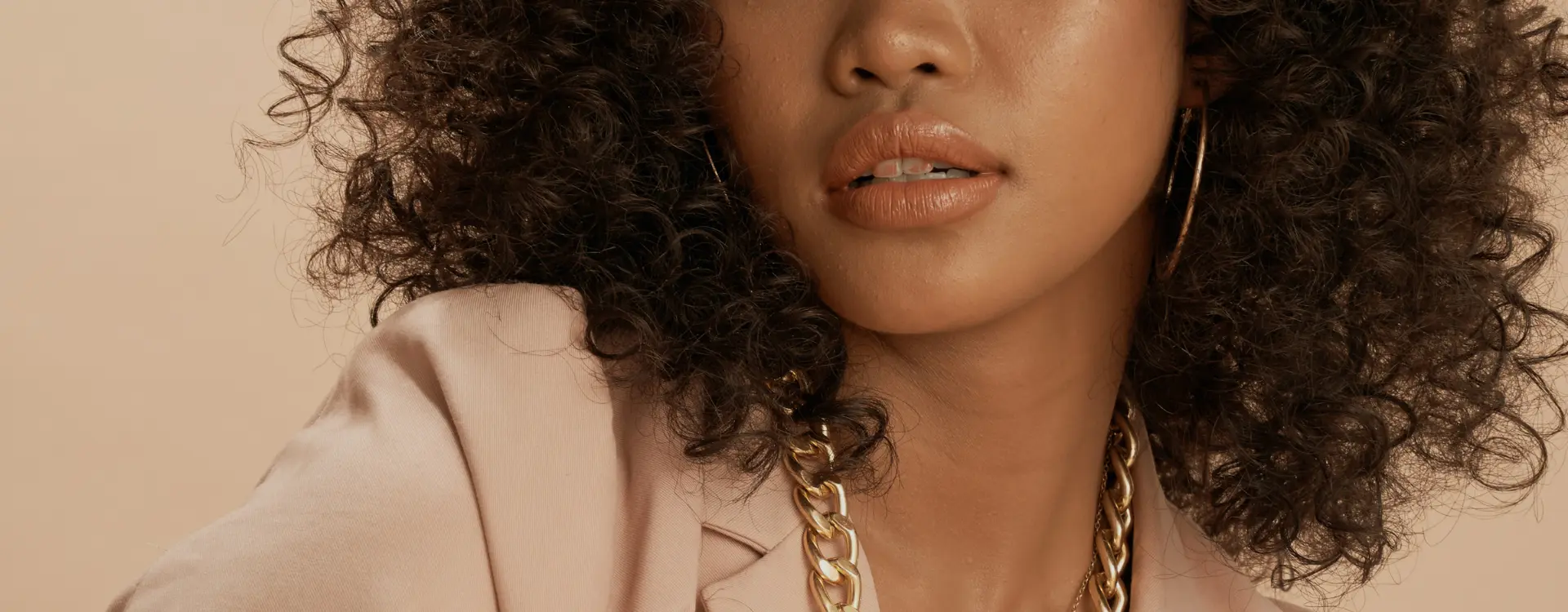A smiling woman with long wavy blonde hair resting her hand beneath her chin against a tan backdrop, the photo on Bellava’s neck lift page