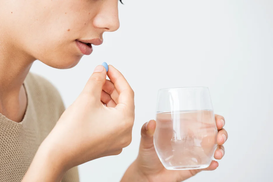 a woman taking a pill to address reactions duue to lip fillers