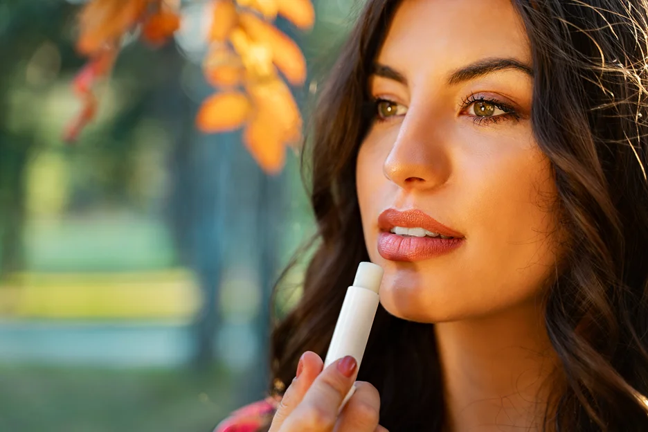 a woman applies lip balm on her lips