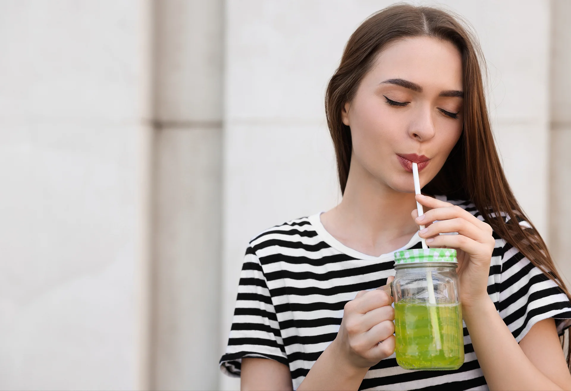 a woman uses straw in sipping the juice from the glass|a woman sips from a cup of iced coffee using straw|lip fillers
