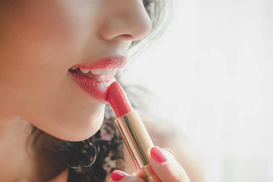 a woman applies lipstick on her lips