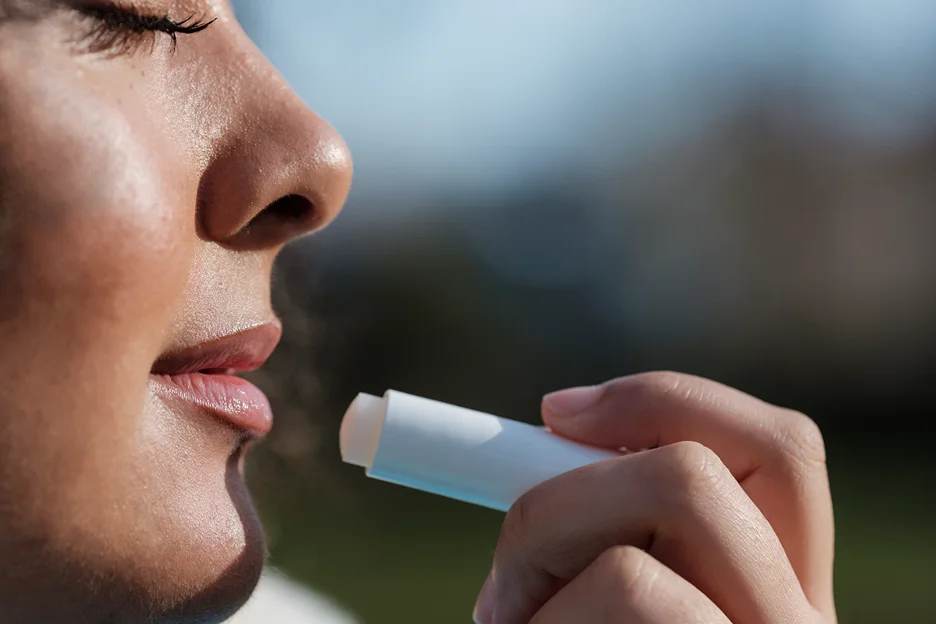 a woman is using lip balm on her lips