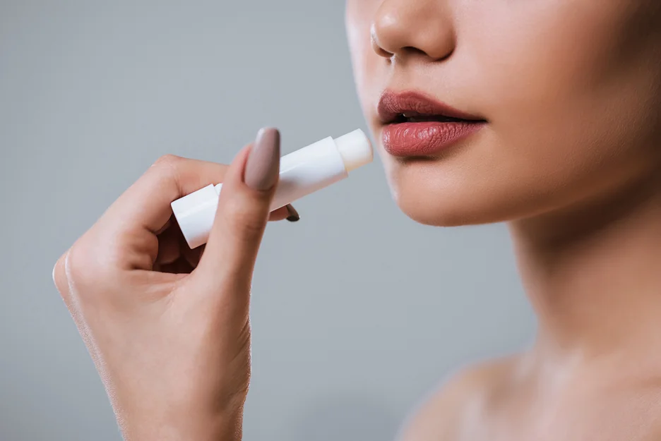 a woman applies lip balm on her lips