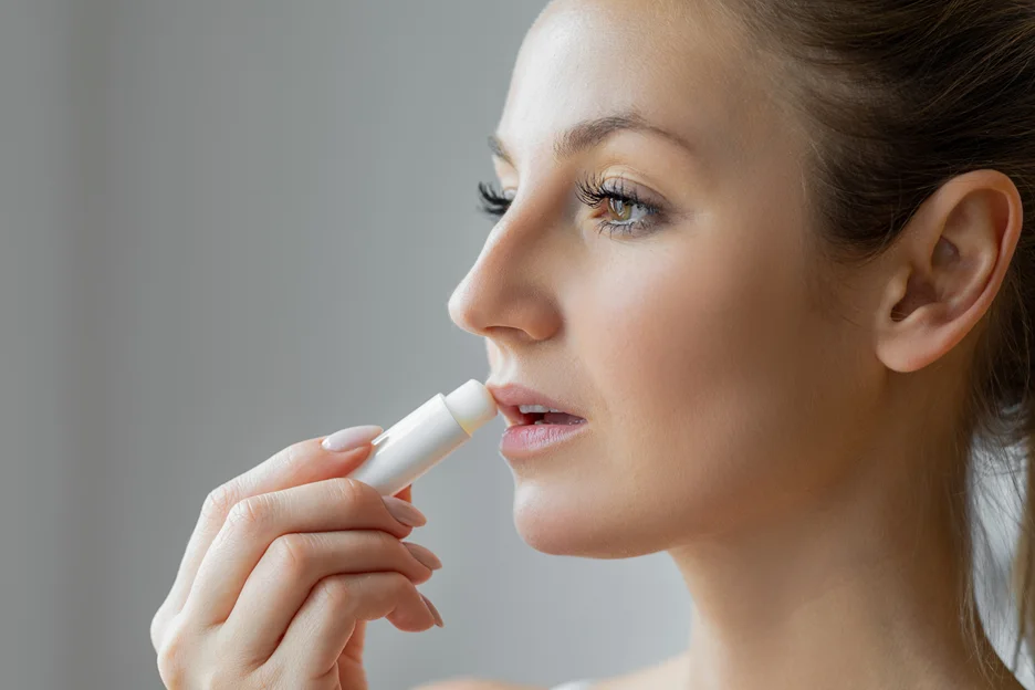 a woman applies lip balm after top lip fillers