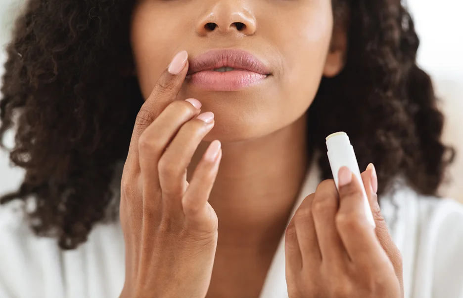 a woman gently massages her lips with lip balm after restylane kysse lip filler injections