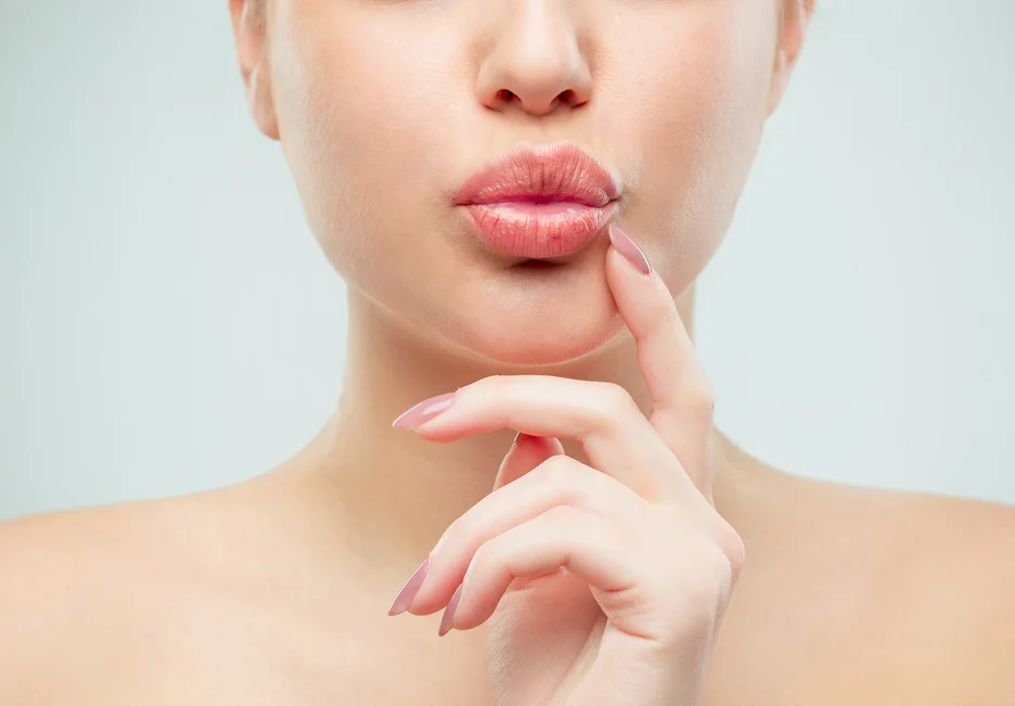 a woman touches her lips after lip filler treatment