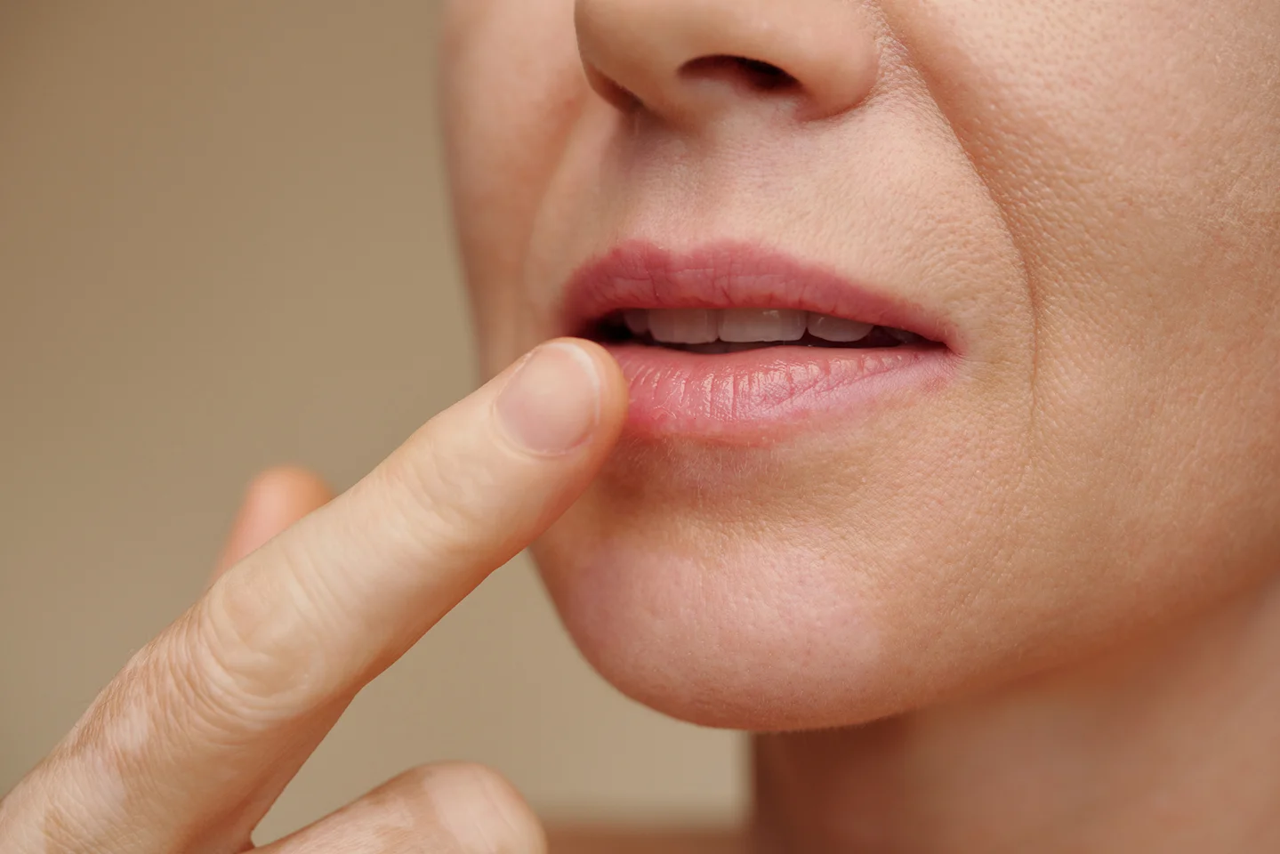 a portrait of a woman touching her lips after lip filler treatment