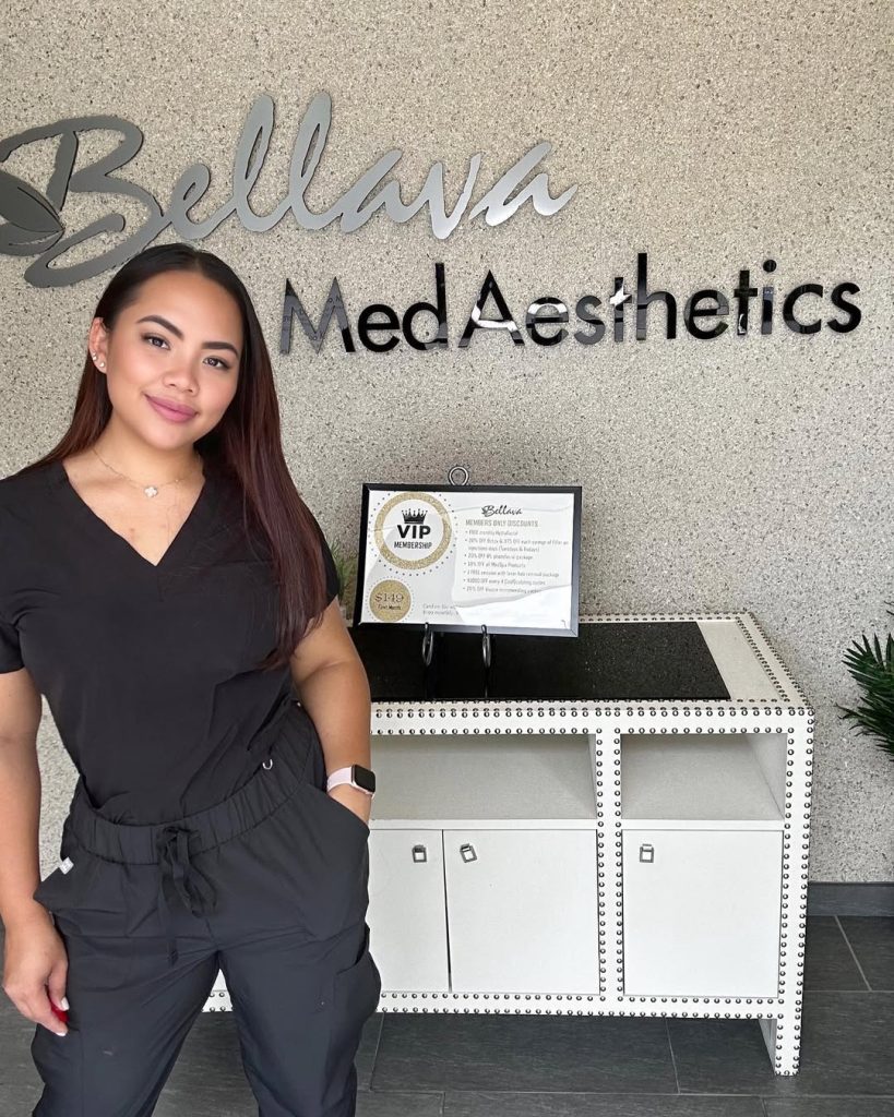 Nurse injector standing at Bellava Med Aesthetics reception area, welcoming patients.